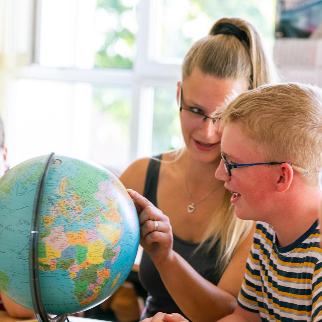 Pädagogin zeigt Kindern die Länder der Erde auf einem Globus